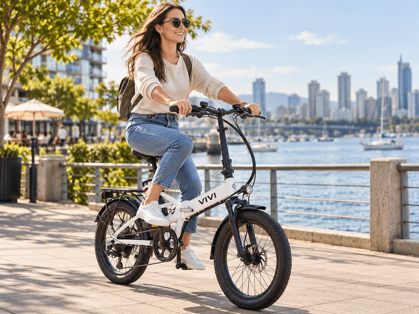 Woman riding a white VIVI folding electric bike along a waterfront path