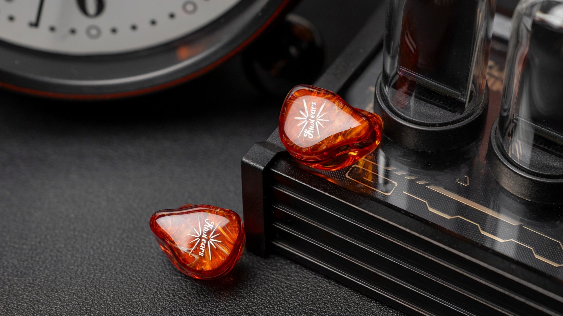 Orange in-ear monitors beside a desktop audio amplifier