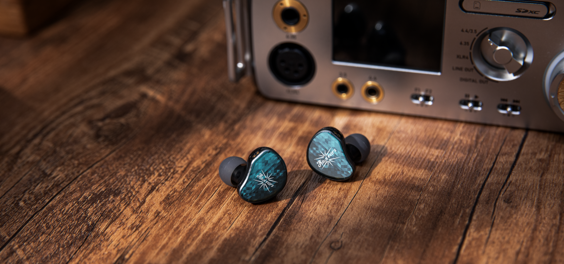 Blue in-ear monitors arranged in front of a desktop audio component