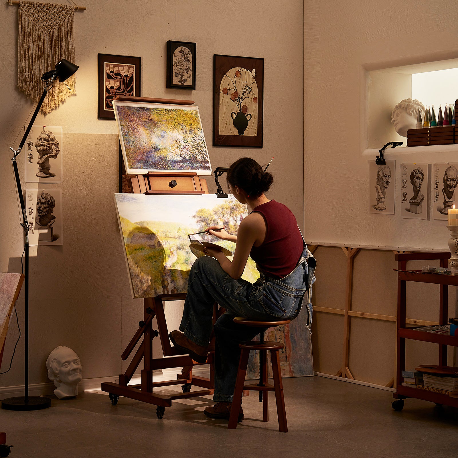 Artist seated at the Walnut DHJ-3 easel with two paintings in a studio