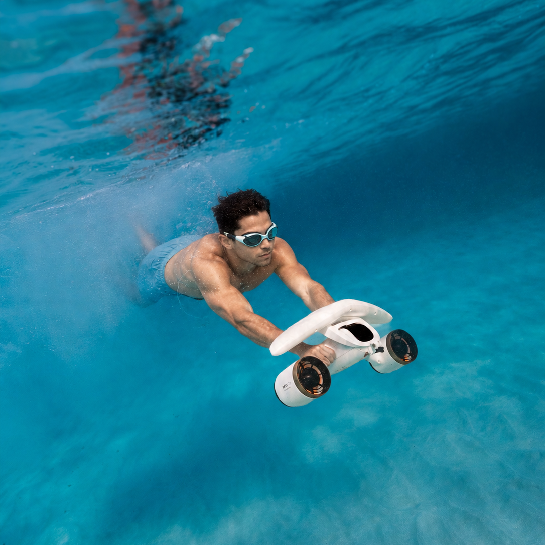 Swimmer holding a white SUBLUE MixPro with gold-colored propeller surrounds underwater