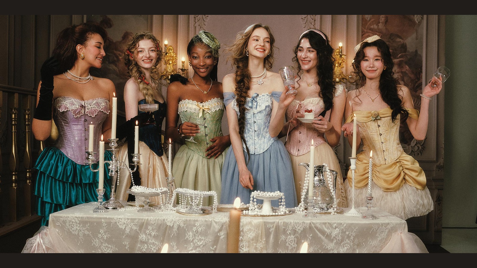 Models wearing colorful LaceMade corset dresses at an elegant table