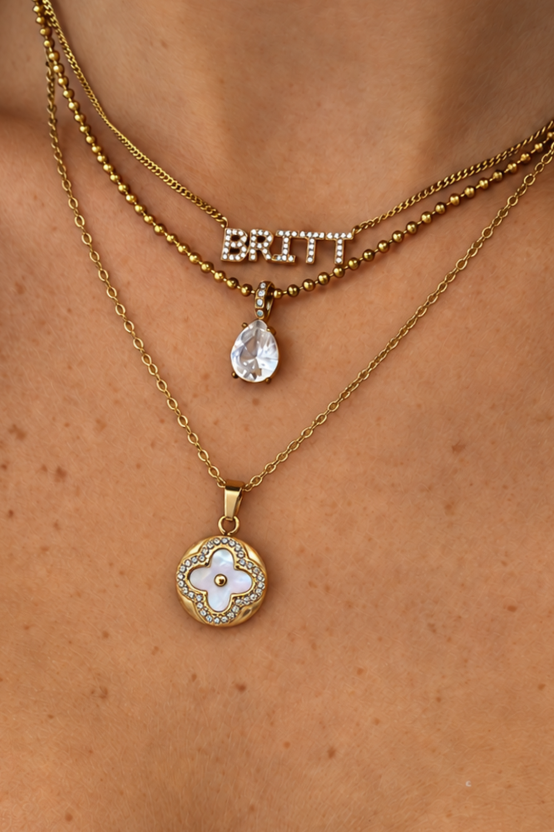 Layered gold-tone EVRY JEWELS necklaces with a name pendant and teardrop crystal