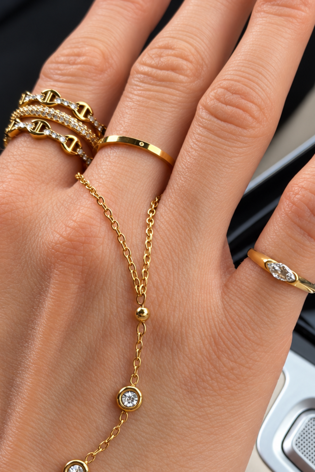 Hand wearing stacked gold-tone EVRY JEWELS rings and a hand chain